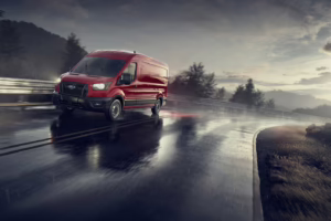 Red van driving through rain on hill